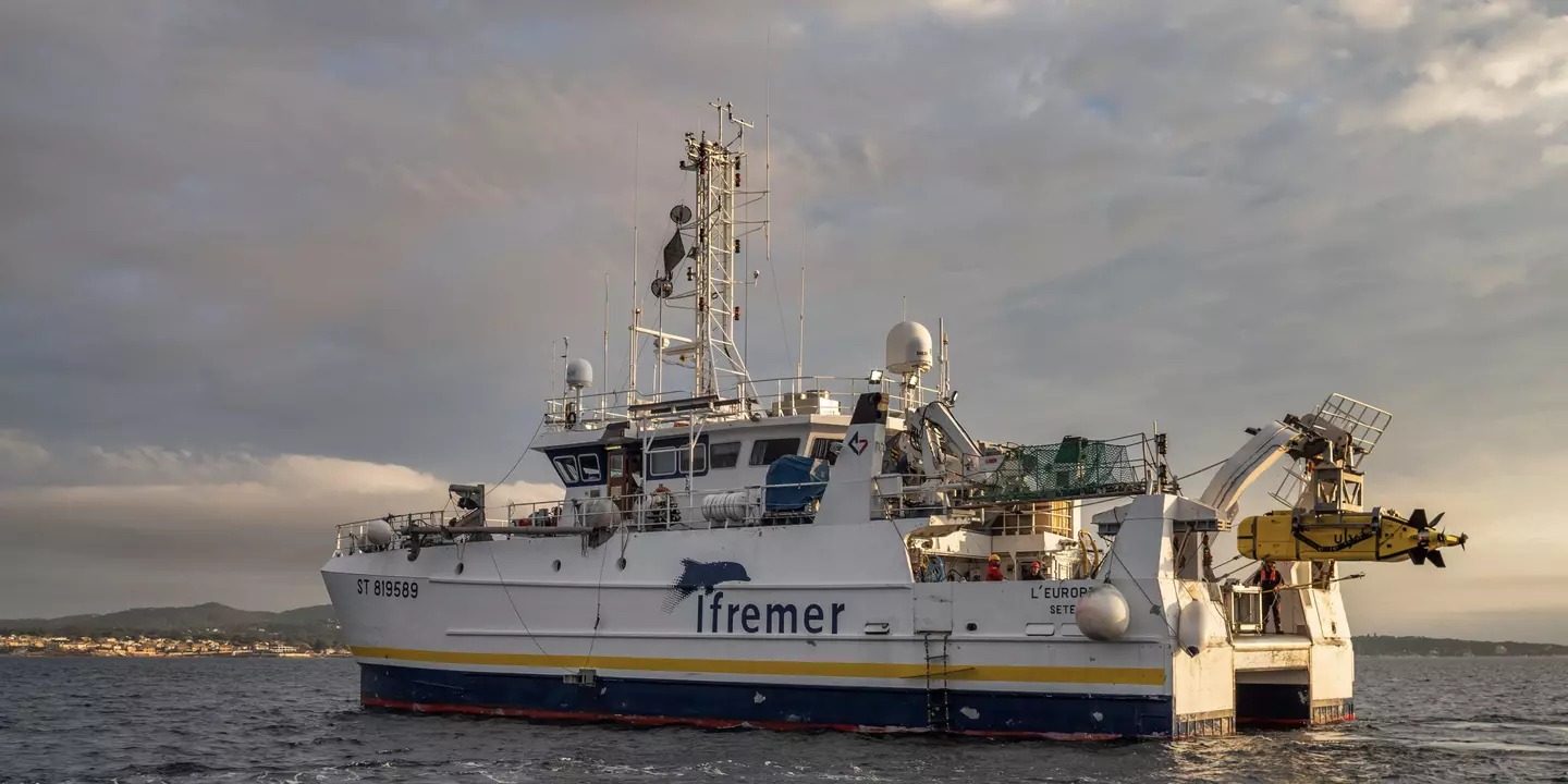 Bateau en mer avec la côte en arrière plan.