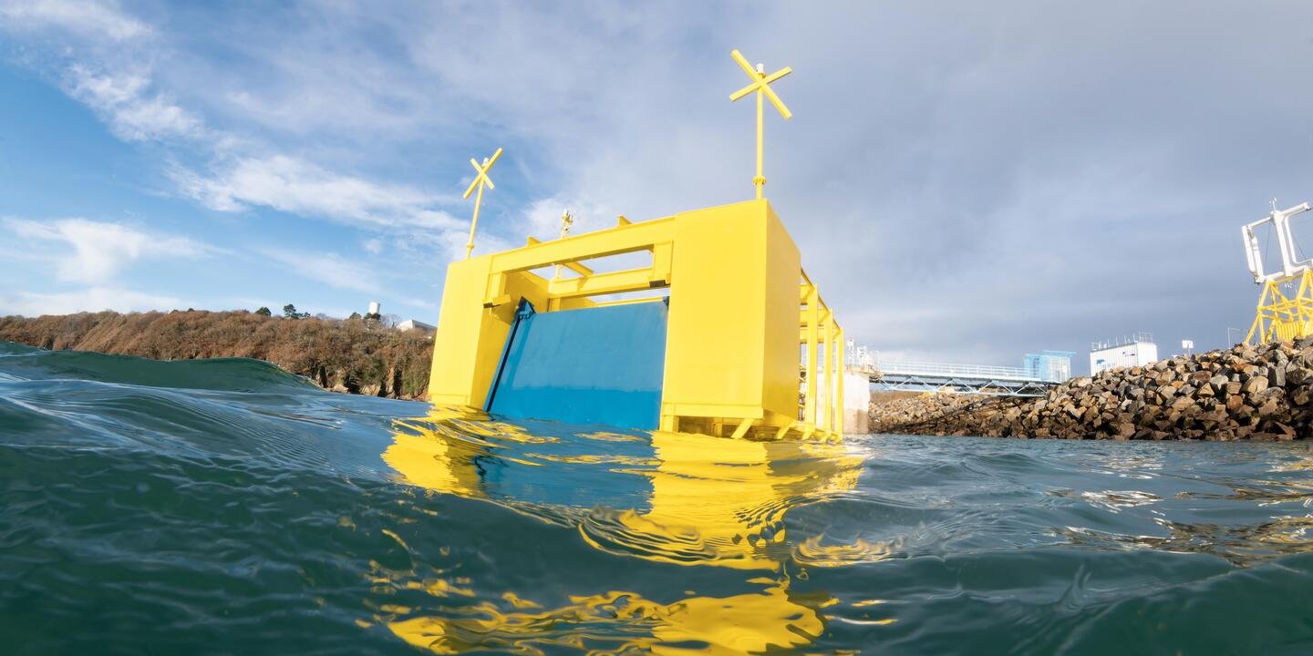 Cube jaune placé sur la mer avec un système de porte bleue mobile. Élément placé devant une digue de port.