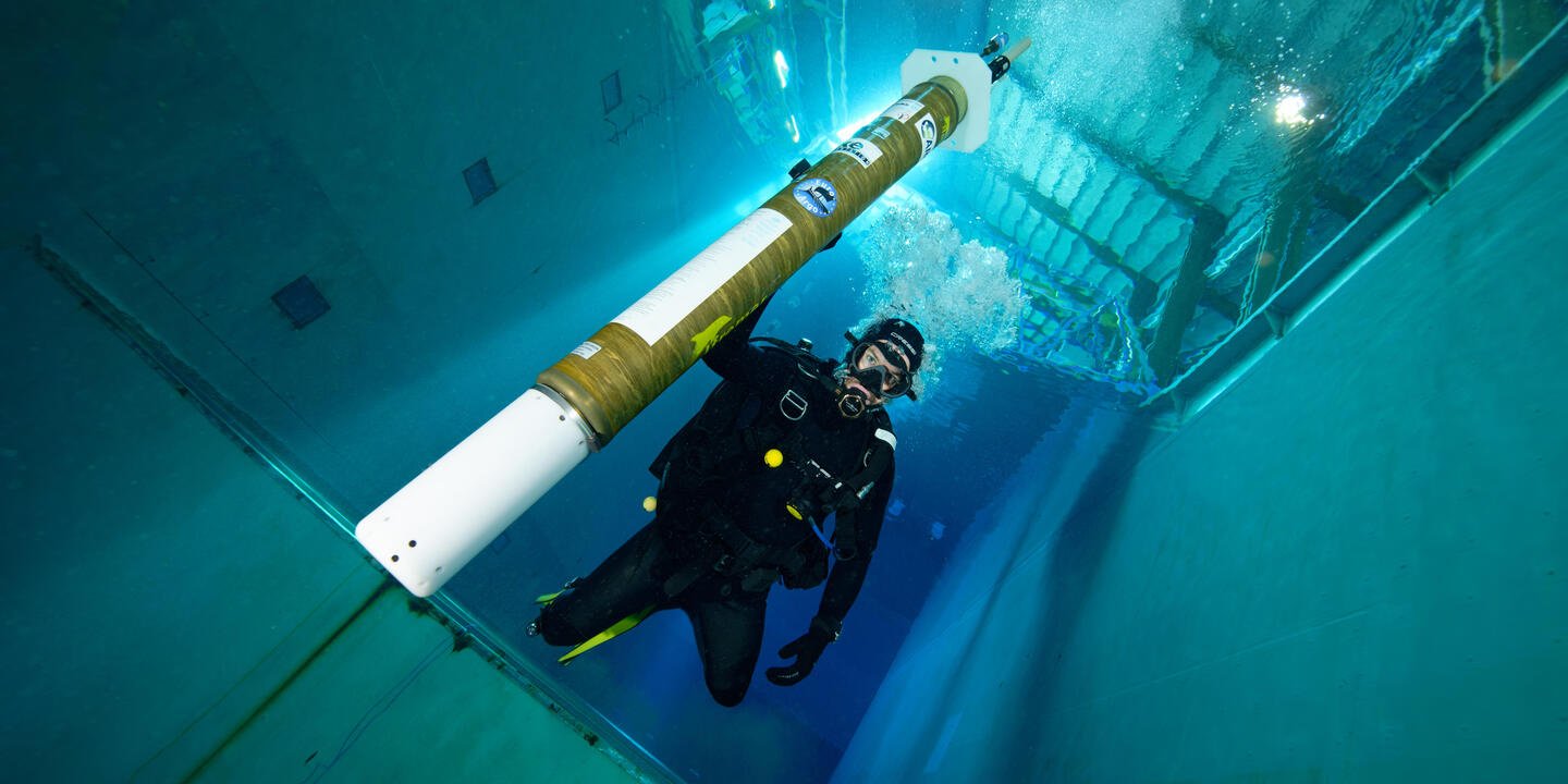 Plongeur à côté d'un profileur dans un bassin, vue en contre plongée.