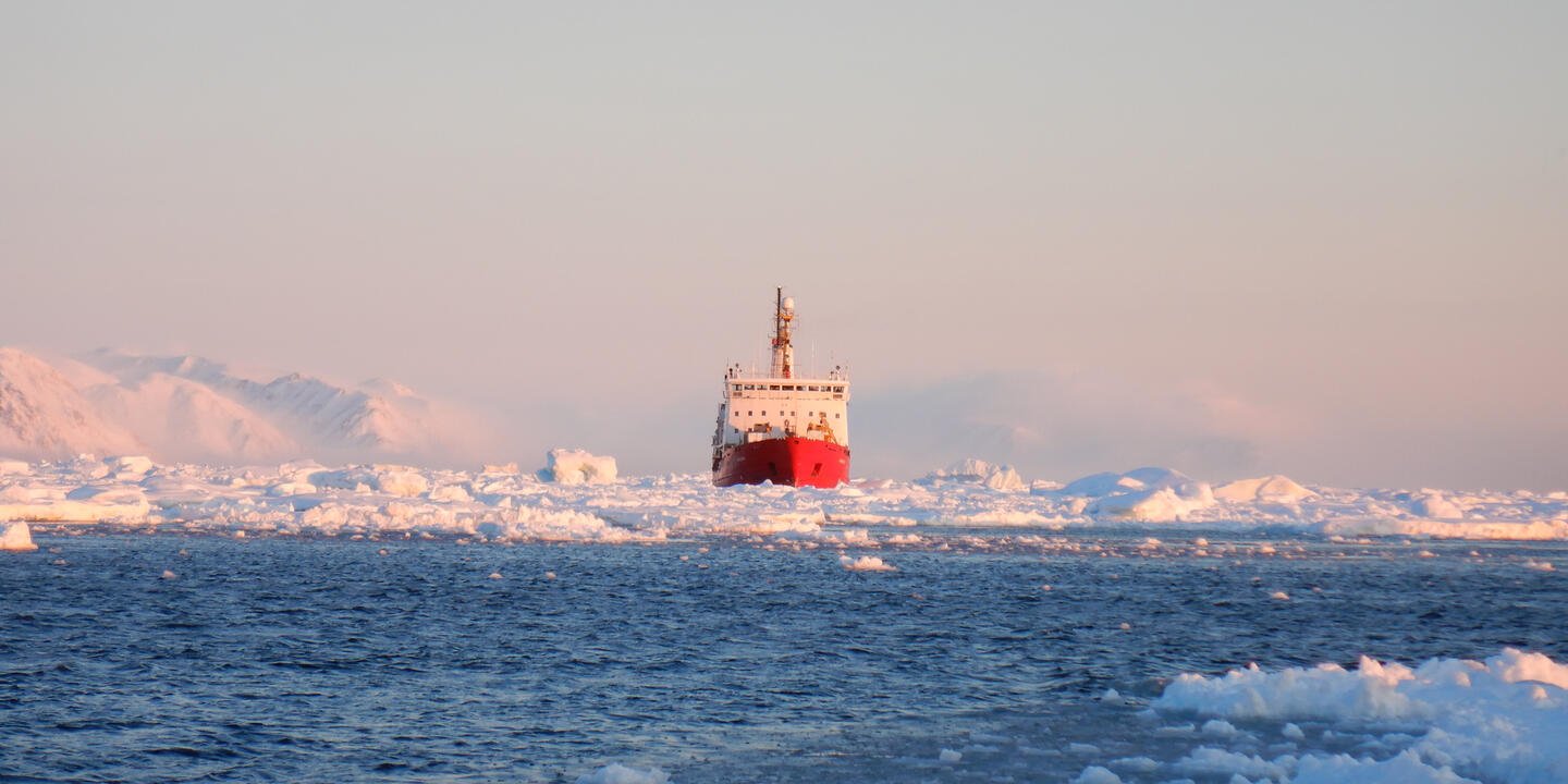 Bateau avec une coque rouge au milieu de la glace Arctique, vue de loin. 