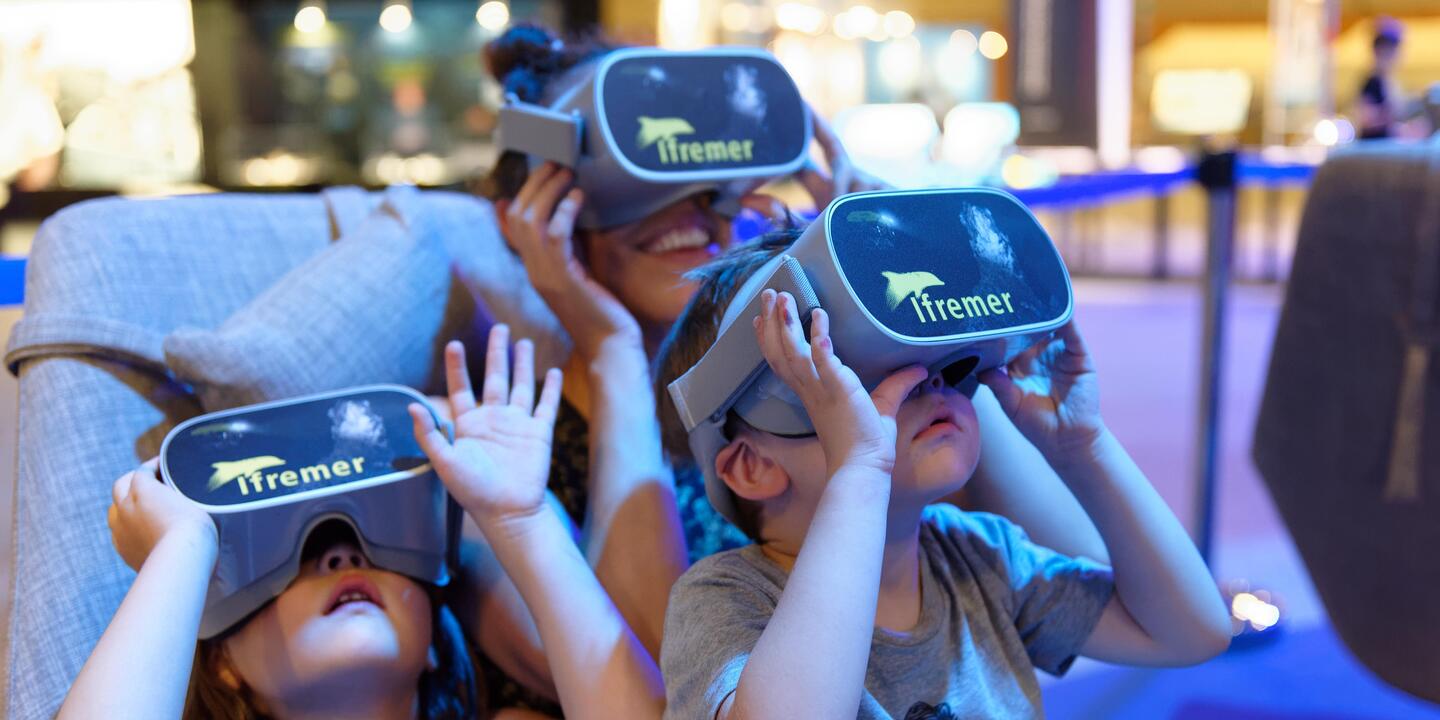 Trois enfants avec des casques de réalité virtuelle qui lève la tête.