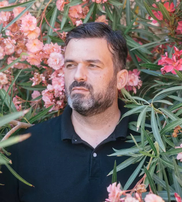 Homme dans un buisson de fleurs roses.