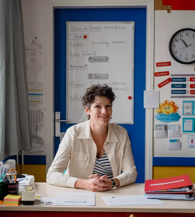 Enseignante assise à son bureau dans une salle de classe.